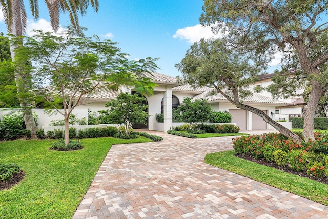 mediterranean / spanish-style home featuring a garage and a front lawn