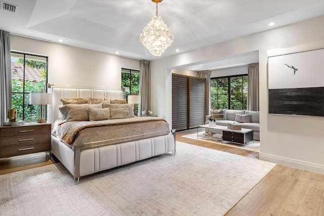 bedroom with multiple windows, light hardwood / wood-style flooring, and a chandelier