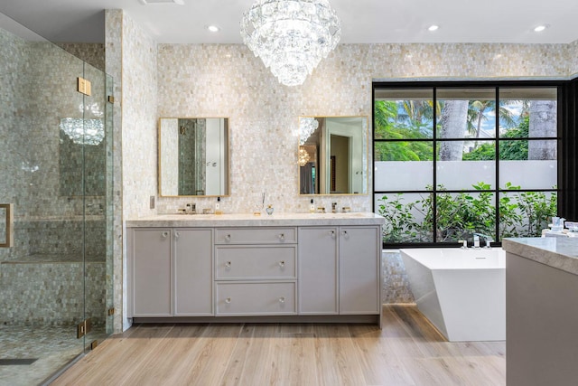 bathroom featuring vanity, hardwood / wood-style flooring, independent shower and bath, and a chandelier