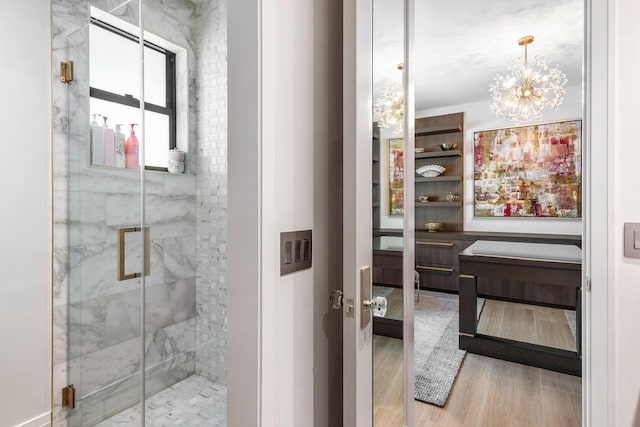 bathroom with an inviting chandelier, wood-type flooring, and walk in shower