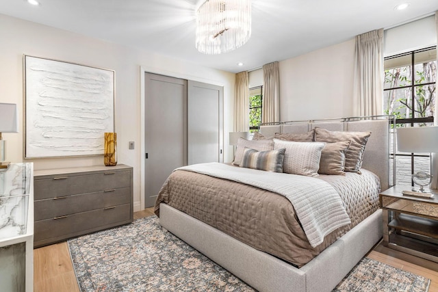 bedroom with light hardwood / wood-style floors, a closet, and a chandelier