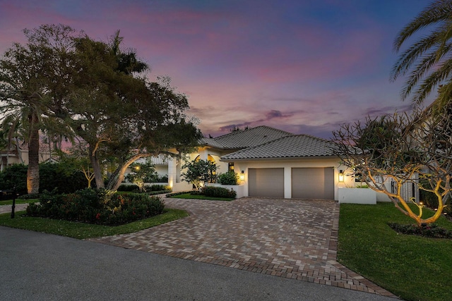 mediterranean / spanish-style home with a garage and a lawn