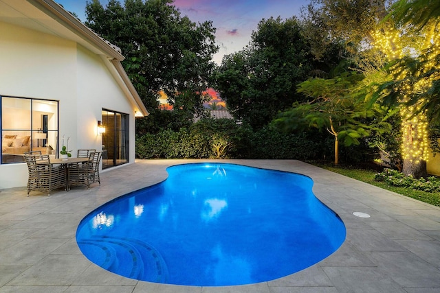 pool at dusk with a patio area