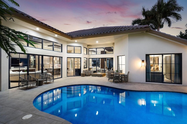 back house at dusk featuring a patio