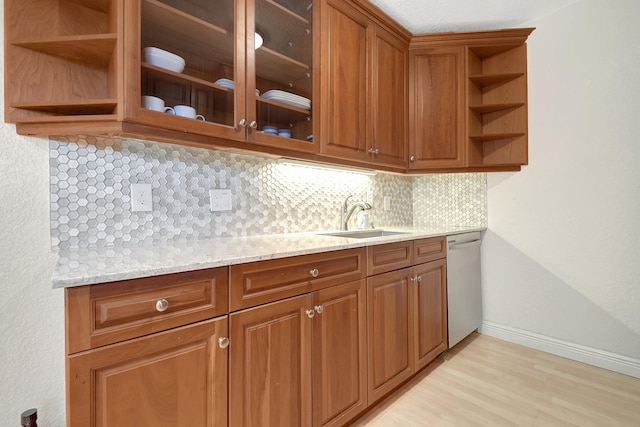 kitchen featuring light stone counters, sink, backsplash, and dishwasher