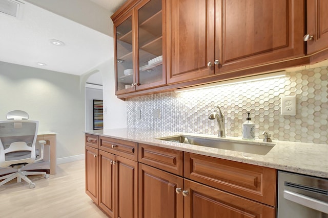 kitchen featuring light stone counters, light hardwood / wood-style floors, sink, and decorative backsplash