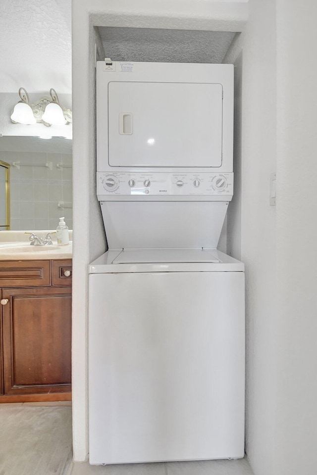 clothes washing area with stacked washing maching and dryer and sink