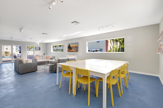 dining space featuring rail lighting and concrete floors