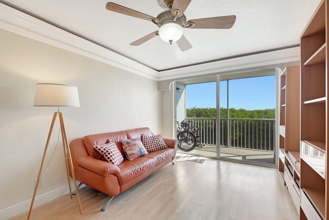 living room with ornamental molding, ceiling fan, and light wood-type flooring