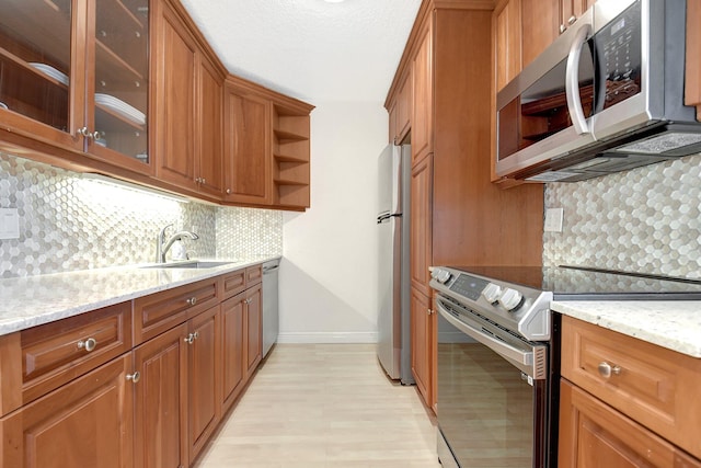 kitchen featuring tasteful backsplash, light stone countertops, stainless steel appliances, and sink