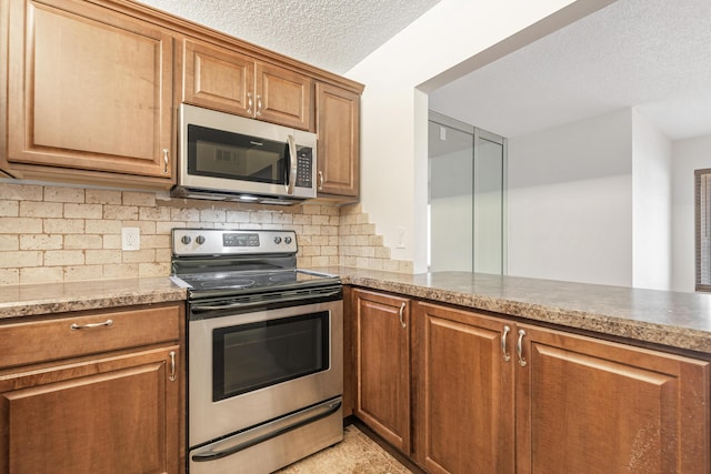 kitchen featuring stainless steel appliances, backsplash, a textured ceiling, and kitchen peninsula