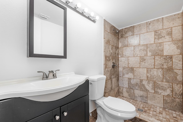 bathroom with vanity, toilet, and a tile shower