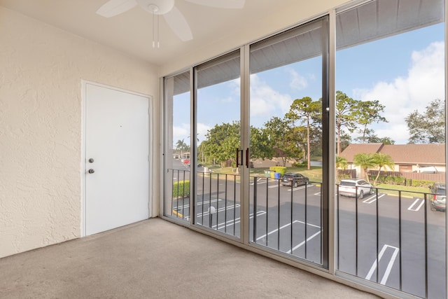 doorway with ceiling fan and carpet flooring