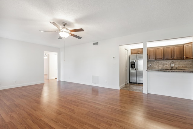 unfurnished living room featuring hardwood / wood-style floors, a textured ceiling, and ceiling fan