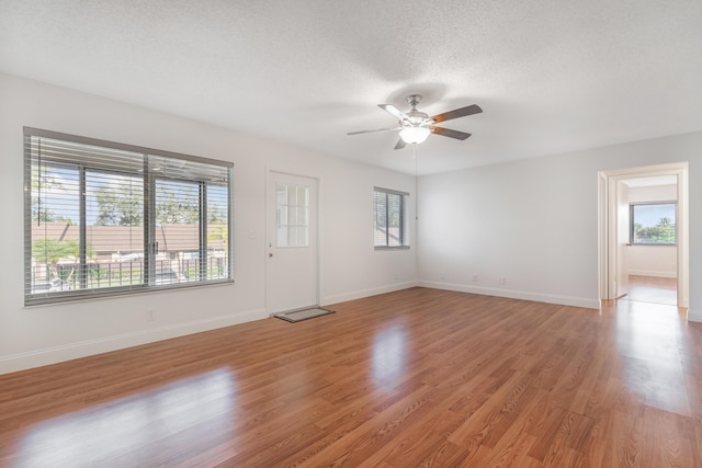 spare room featuring ceiling fan, a wealth of natural light, light hardwood / wood-style floors, and a textured ceiling