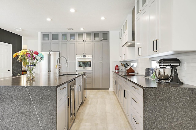 kitchen featuring a kitchen island with sink, stainless steel appliances, a sink, visible vents, and backsplash