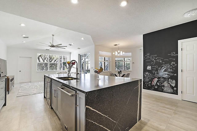 kitchen with dark countertops, recessed lighting, a sink, dishwasher, and ceiling fan with notable chandelier