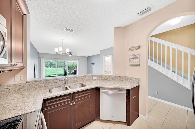 kitchen with sink, an inviting chandelier, a textured ceiling, light tile patterned floors, and stainless steel dishwasher