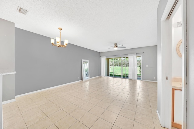 tiled empty room featuring ceiling fan with notable chandelier and a textured ceiling