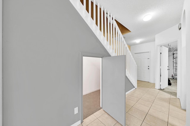 stairway featuring tile patterned floors and a textured ceiling