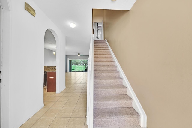 staircase featuring tile patterned floors and ceiling fan