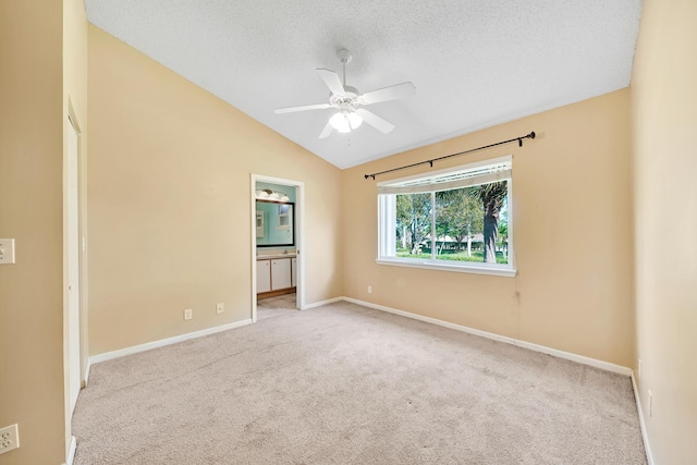 empty room featuring ceiling fan, lofted ceiling, light colored carpet, and a textured ceiling