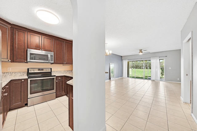 kitchen with light tile patterned floors, appliances with stainless steel finishes, dark brown cabinetry, a textured ceiling, and decorative light fixtures