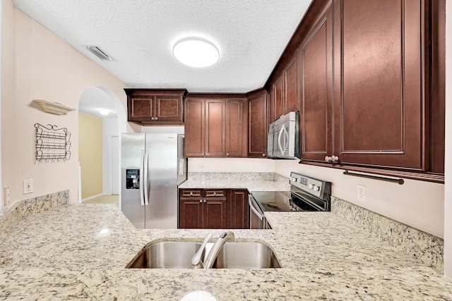 kitchen featuring light stone counters, sink, a textured ceiling, and appliances with stainless steel finishes