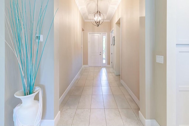 hall featuring light tile patterned floors, baseboards, an inviting chandelier, and crown molding