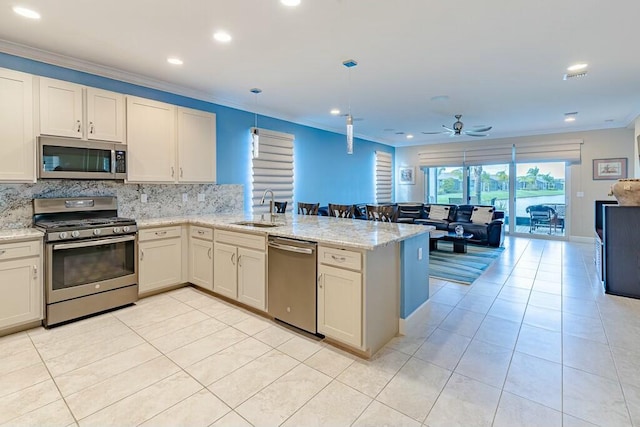 kitchen featuring ornamental molding, a sink, a peninsula, appliances with stainless steel finishes, and light tile patterned floors