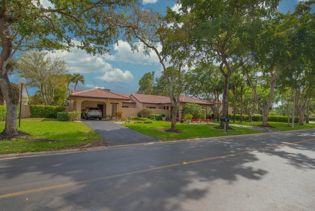 view of front of property with aphalt driveway, stucco siding, an attached garage, a tiled roof, and a front lawn