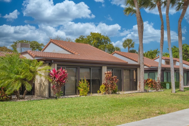 back of property featuring a yard and a tiled roof