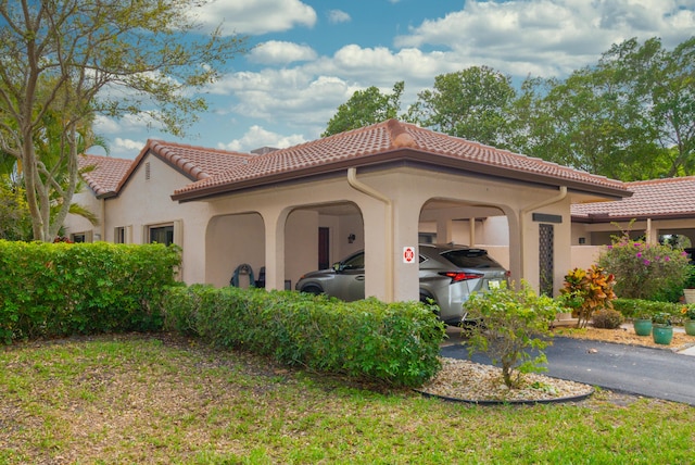 view of home's exterior featuring a carport, aphalt driveway, a tiled roof, and stucco siding