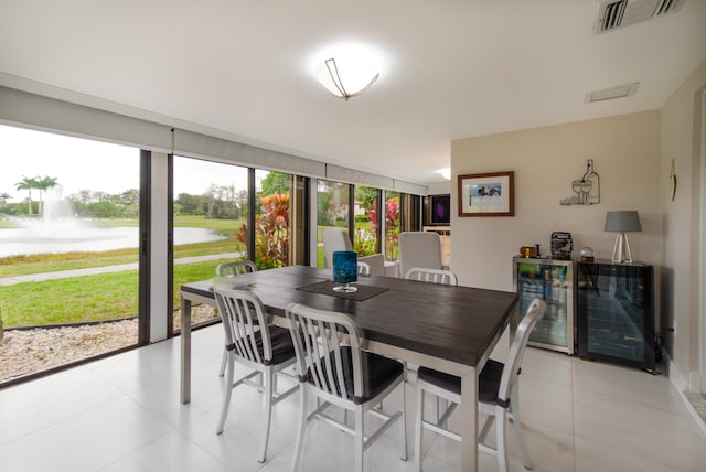 dining area featuring a water view, light tile patterned floors, wine cooler, and visible vents