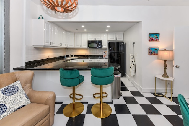 kitchen with a breakfast bar, backsplash, black appliances, white cabinets, and kitchen peninsula