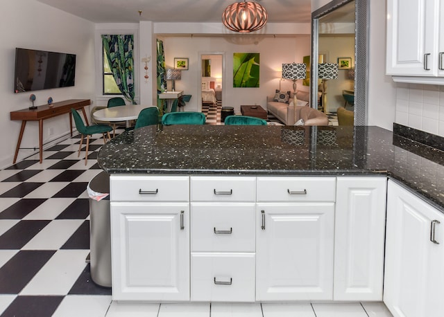 kitchen with white cabinetry, backsplash, and dark stone countertops