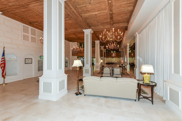 tiled living room featuring an inviting chandelier, decorative columns, and wooden ceiling