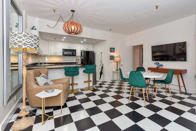 kitchen featuring tasteful backsplash, white cabinetry, sink, hanging light fixtures, and black appliances