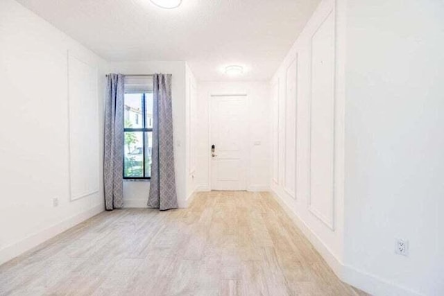 unfurnished room with a textured ceiling and light wood-type flooring