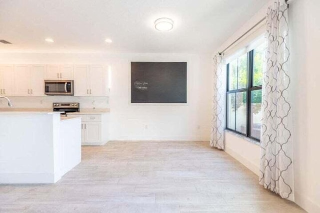 kitchen featuring white cabinetry, light hardwood / wood-style flooring, and range