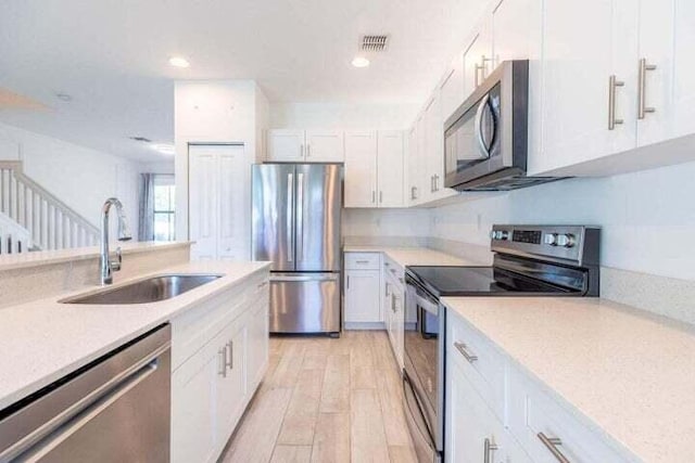 kitchen with white cabinetry, appliances with stainless steel finishes, light hardwood / wood-style floors, and sink