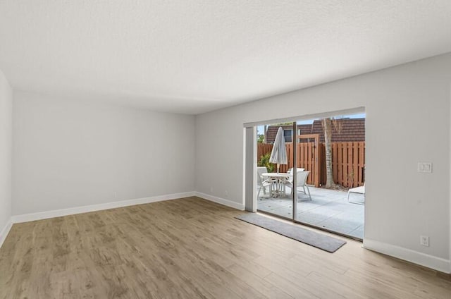 spare room featuring a textured ceiling and light hardwood / wood-style floors