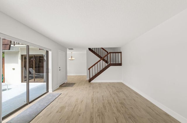 spare room with plenty of natural light, a notable chandelier, and light hardwood / wood-style flooring