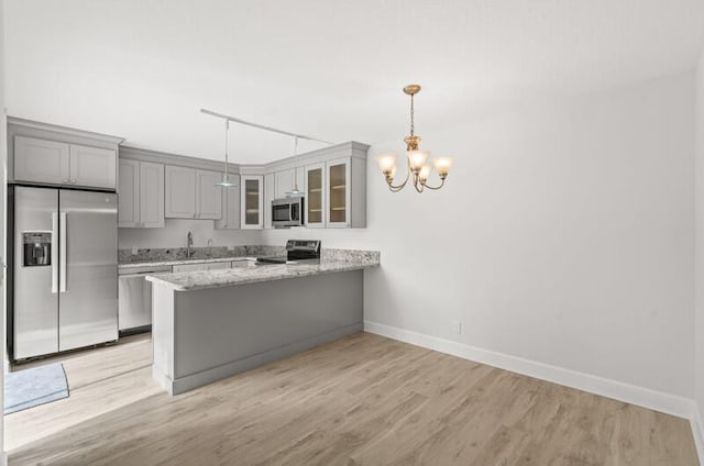 kitchen featuring decorative light fixtures, light hardwood / wood-style floors, kitchen peninsula, stainless steel appliances, and an inviting chandelier