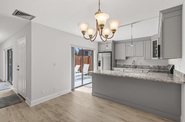 kitchen with pendant lighting, stainless steel fridge, gray cabinets, range, and light stone countertops