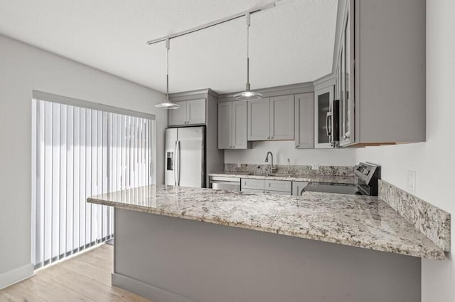 kitchen featuring sink, gray cabinets, stainless steel appliances, decorative light fixtures, and kitchen peninsula