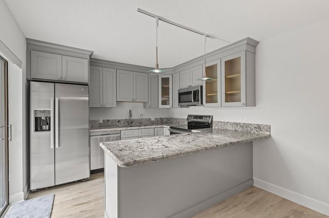 kitchen featuring appliances with stainless steel finishes, sink, gray cabinetry, kitchen peninsula, and light hardwood / wood-style flooring