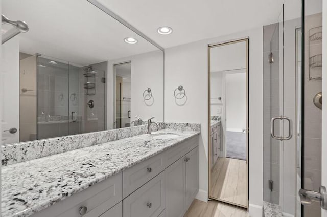 bathroom with hardwood / wood-style flooring, vanity, and a shower with door