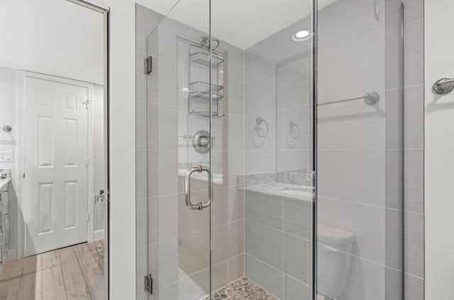 bathroom with hardwood / wood-style flooring and a shower with shower door