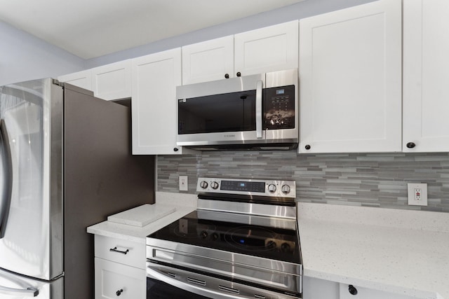 kitchen with white cabinetry, light stone countertops, tasteful backsplash, and stainless steel appliances